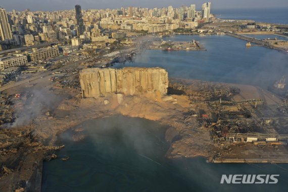 [베이루트=AP/뉴시스] 레바논 베이루트 항구에서 폭발사건이 발생한 다음 날인 5일(현지시간)에도 연기가 피어오르고 있다. 초대형 폭발로 파괴된 창고 건물의 일부가 서있고, 그 앞의 땅이 분화구처럼 함몰돼있는 것이 보인다. 2020.08.06