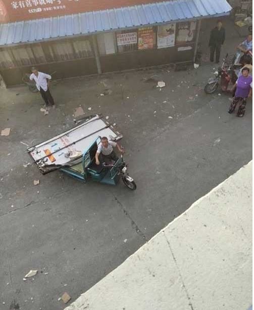 지난 4일 중국 장쑤성 옌청의 한 고속도로 인근 주민이 전복된 화물트럭에서 뒷문이 떨어지자, 이를 삼륜 오토바이에 실어가고 있다. 중국 매체 양즈완바오 캡쳐.
