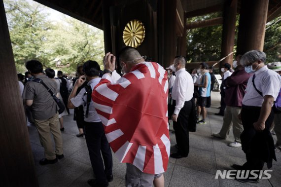 태평양전쟁 패전 75주년을 맞은 15일 일본 도쿄의 야스쿠니 신사에서 한 남성이 욱일기를 몸에 두르고 입장을 기다리고 있다. AP뉴시스