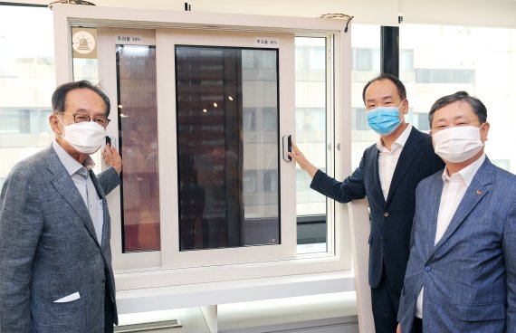전승태 SK건설 건축주택사업부문장(오른쪽 첫번째)과 홍성철 알루이엔씨 대표(가운데), 최재원 국영지앤엠 대표가 개폐되는 창에 태양광 발전시스템을 구현해 시연하고 있다. SK건설 제공