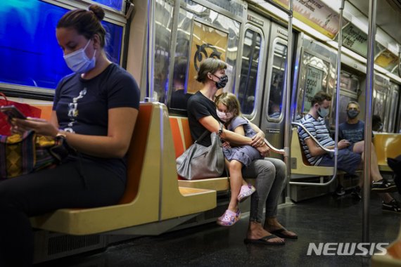 뉴욕의 지하철 안에서 마스크를 쓴 한 여자아이가 엄마의 무릎에 앉아 쉬고 있다. /사진=AP뉴시스