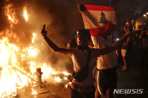 [베이루트=AP/뉴시스]레바논 베이루트 대규모 폭발 참사 이후 반정부 시위가 이어지는 가운데 11일(현지시간) 시위대가 레바논 국기를 들고 브이(V)를 그려 보이고 있다. 2020.08.12.