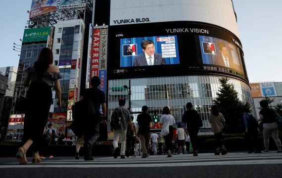 일본 도쿄의 시민들이 28일 대형 모니터를 통해 아베 신조 일본 총리의 사임 발표 회견을 보고 있다. 로이터 뉴스1