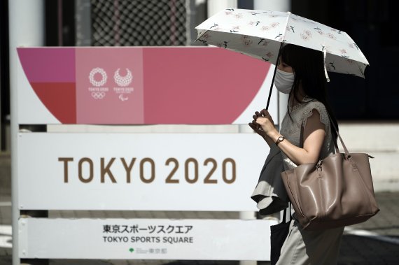 이달 초 한 여성이 코로나19 감염 방지를 위해 마스크를 쓰고, 도쿄올림픽2020 입간판 앞을 지나고 있다. AP뉴시스
