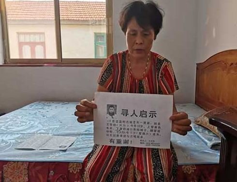 중국 산둥성에서 실종된 싱싱의 어머니가 2002년 당시 실종 포스터를 들어보이고 있다. 산둥상바오 캡쳐.