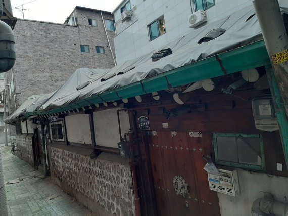 16일 전국 1호 도시재생 활성화 지역인 서울 종로구 창신동 골목길의 한 주택. 새는 비를 막기 위해 설치한 지붕의 임시 가림막이 주변 신축 빌라와 대조를 이루고 있다. 창신동 공공재개발 준비위원회 제공