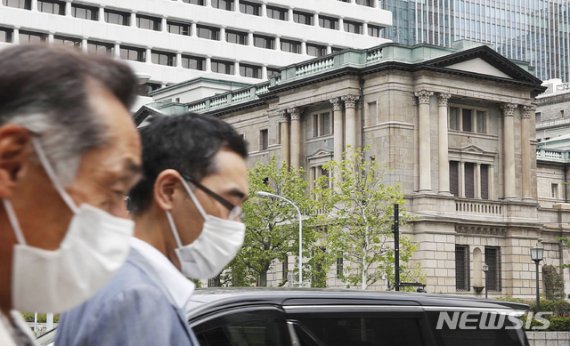 [도쿄=AP/뉴시스]27일 일본 도쿄에 위치한 일본은행 앞으로 마스크를 쓴 시민들이 걸어가고 있다. 2020.04.27.
