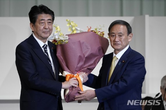 스가 요시히데 일본 총리가 지난 14일 아베 전 총리로 부터 꽃다발을 받고 있다. 스가 총리는 이날 일본 집권여당인 자민당 총재로 부임했다. 사진=AP뉴시스