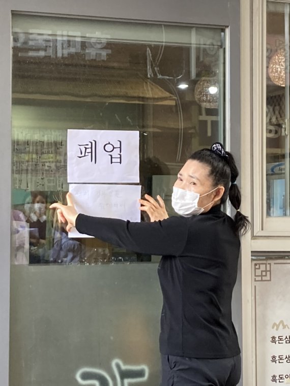 서울 신대방동에서 흑돈연가를 운영하던 소상공인 손원주씨가 18일 매장 앞에 '폐업' 안내문을 붙이고 있다. 소상공인연합회 제공