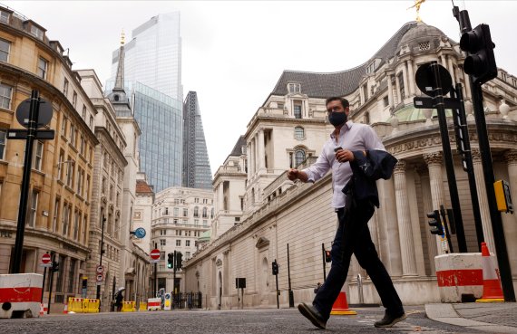 지난 23일(현지시간) 마스크를 착용한 시민이 영국 런던의 썰렁한 금융가를 걸어가고 있다.로이터뉴스1