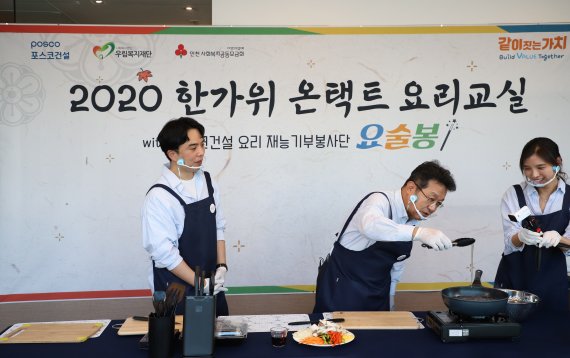 포스코건설 한성희 사장과 요리재능기부봉사단이 함께 유튜브로 추석요리 만들기 시범을 보이고 있다.