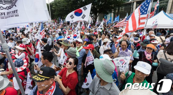 보수단체 회원들이 지난 2018년 제73주년 광복절에 서울 광화문네거리에서 문재인 대통령 탄핵촉구 집회를 열고 태극기와 성조기를 흔들고 있다. 뉴스1