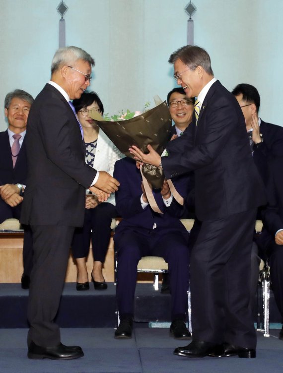 문재인 대통령이 2017년 6월 청와대에서 열린 강경화 외교부장관 임명식에서 강 장관의 남편인 이일병 교수(왼쪽)에게 꽃다발을 주고 있다. 뉴스1