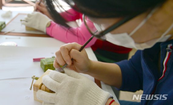 한글날인 9일 광주 광산구 소촌동 용아생가에서 열린 '아시별' 한글날 행사에서 한 학부모가 자녀의 한글 이름이 새겨진 도장을 만들고 있다. 뉴시스 제공