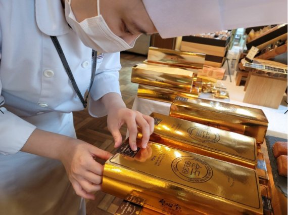 한국조폐공사와 대전지역 대표 제과업체 성심당이 협업해 만든 골드바 모양의 피낭시에 케익 '순도 99.99'를 성심당 직원이 판매대에 올리고 있다.