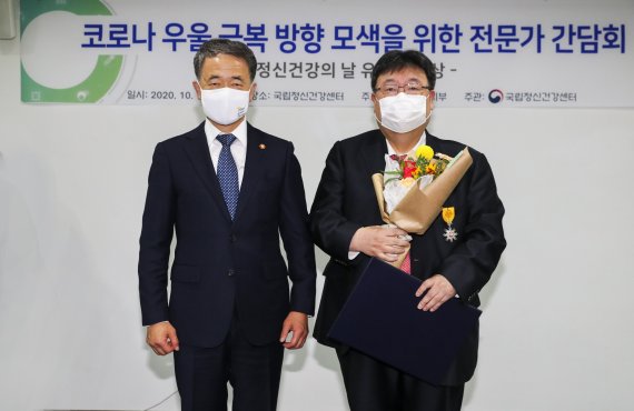 국제성모병원 정신건강의학과 기선완 교수(오른쪽)가 박능후 보건복지부 장관에게 국민포산을 수여받은 후 기념촬영을 하고 있다. 국제성모병원 제공