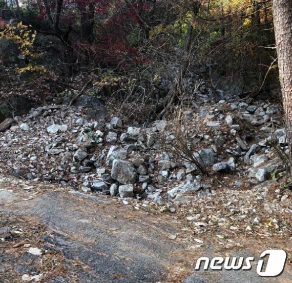 지난 8월 집중호우로 인한 도로침수 개울에서 떠내려온 돌들이 쌓여 돌무덤 형태로 방치된 모습 © 뉴스1