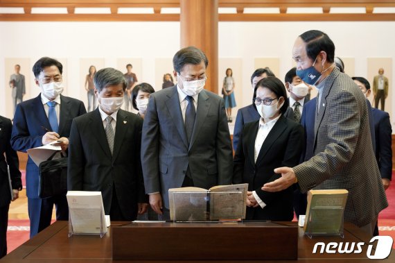 문재인 대통령이 12일 청와대 본관에서 열린 고(故) 전태일 열사 훈장 추서식에서 유가족에게 국민훈장 무궁화장을 수여한 후 환담장으로 이동 중 로비에 전시된 전태일 평전 및 태일실업 설립 계획서를 보며 대화하고 있다. 2020.11.12/뉴스1 © News1 유승관 기자