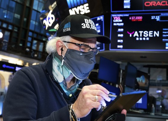 지난 24일(현지시간) 미국 뉴욕 뉴욕증권거래소(NYSE)에서 한 중개인이 '다우 30000'이라고 적힌 모자를 쓰고 거래를 하고 있다.AP뉴시스