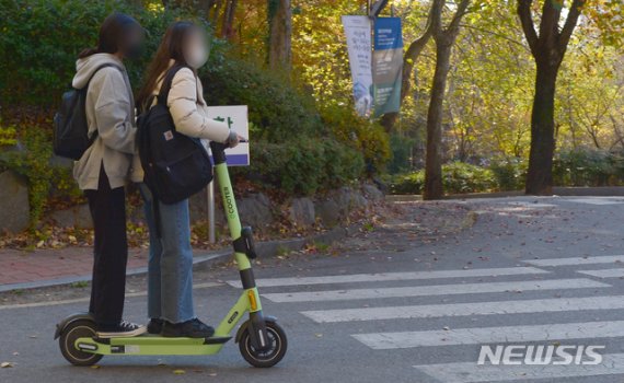 [광주=뉴시스] 김민국 기자 = 지난 12일 오후 광주 북구 용봉동 한 캠퍼스에서 2명의 이용객이 한 대의 전동 킥보드를 탄 채 달리고 있다. 2020.11.15. blank95@newsis.com