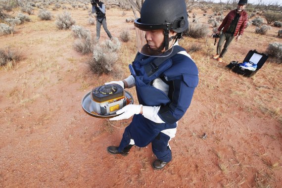 일본 우주항공연구개발기구(JAXA)의 한 연구원이 지난 6일 호주 남부 사막에 떨어진 소행성 류구의 물질이 담긴 캡슐을 수거하고 있다. 캡슐은 일본의 소행성 탐사선인 하야부사2가 지난 5일 우주공간에서 지구로 떨어뜨린 것이다. AP뉴시스