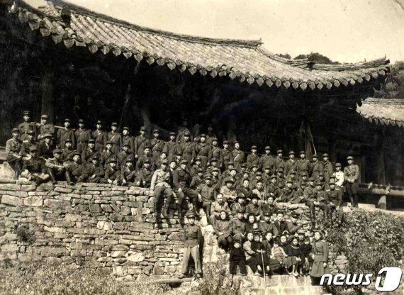1949년 10월 김일성 수상이 인민군 대원들과 함께 천주사를 방문해 천주루 앞에서 기념촬영하고 있다. 4번째 줄 가운데에 김일성 수상이 앉아 있고, 맨 앞줄에 어린 김정일(왼쪽에서 3번째)의 모습이 보인다. (미디어한국학 제공) 2020.12.12.© 뉴스1