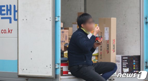 서울 시내 한 택배 물류센터에서 한 기사가 배송준비를 하다 짐칸에서 라면을 먹고 있다. 뉴스1 제공
