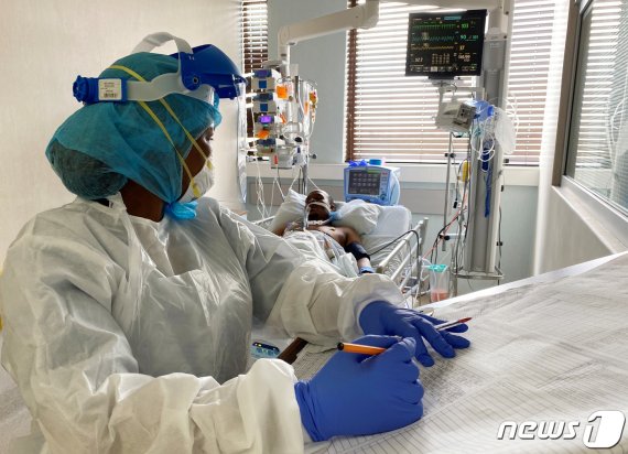 지난 25일 남아프리카공화국 켐프턴파크의 한 의료시설에서 의료진이 코로나19 환자를 진료하고 있다. © 로이터=뉴스1