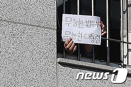 6일 오후 서울 송파구 동부구치소에서 한 재소자가 '무능한 법무부, 무능한 대통령'이라는 문구가 적힌 종이를 창살 너머로 꺼내 보이고 있다. 2021.1.6/뉴스1 /사진=뉴스1화상