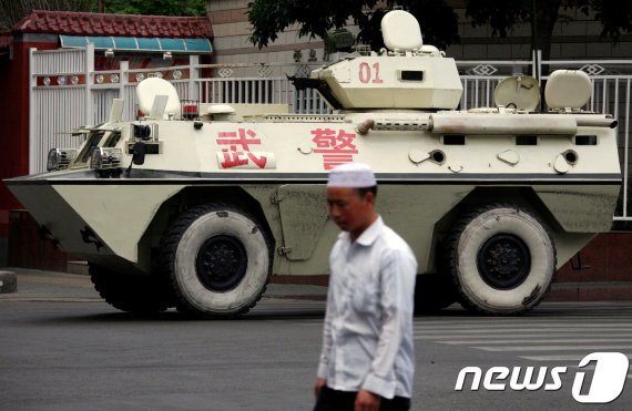 신장성의 성도인 우루무치에서 한 위구르인이 중국 무장경찰의 장갑차 앞을 지나가고 있다. 중국은 무장경찰을 배치해 위구르인의 일거수일투족을 감시하고 있다. © 로이터=뉴스1 © News1 박형기 기자 /사진=뉴스1