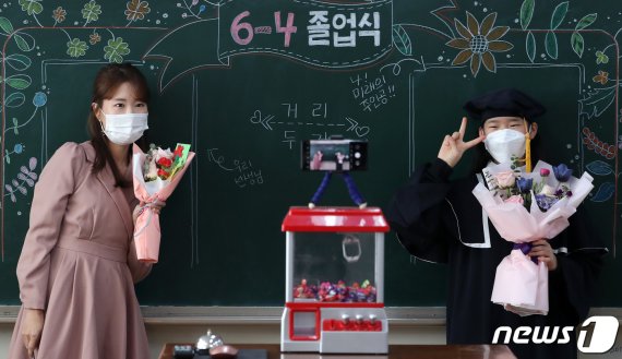 13일 서울 노원구 태랑초등학교에서 비대면 온라인 졸업식이 끝난 뒤 학사모와 졸업가운을 반납하기 위해 학교를 찾은 한 학생이 서채린 담임교사와 기념사진을 찍고 있다./뉴스1 © News1 이동해 기자