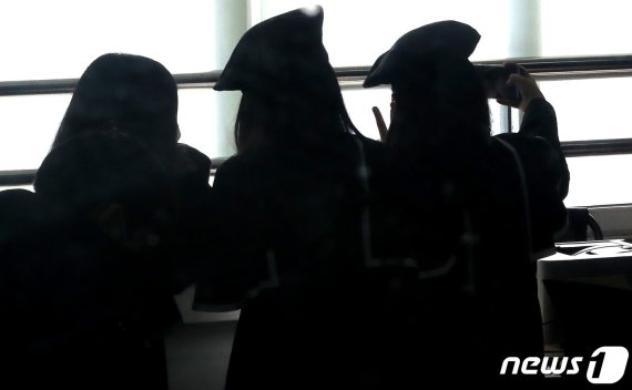 비대면 온라인 졸업식이 진행된 13일 서울 노원구 태랑초등학교에서 졸업식이 끝난 뒤 졸업가운 반납을 위해 학교를 찾은 학생들이 기념사진을 찍고 있다./뉴스1 © News1 이동해 기자