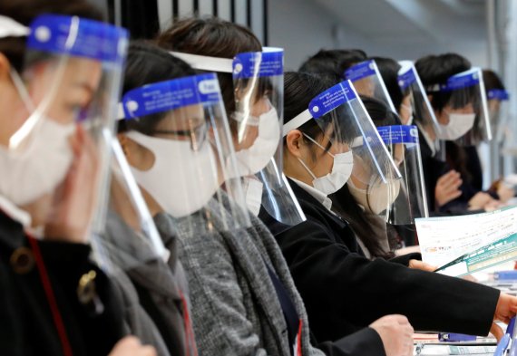 지난 13일 일본 도쿄의 한 전시장 안내 데스크에서 직원들이 코로나19 감염 방지를 위해 투명 안면 보호대와 마스크를 쓴 채 일을 하고 있다. 로이터 뉴스1