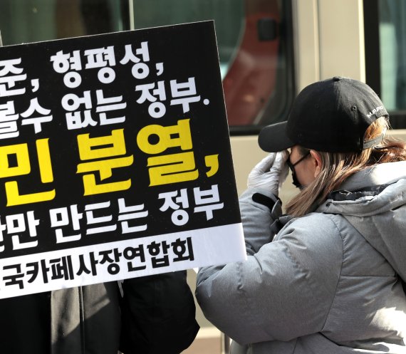 한 카페 사장이 13일 서울 여의도 더불어민주당사 앞에서 열린 전국카페사장연합회 기자회견에서 코로나19 방역으로 인한 규제 완화 촉구 성명서 발표를 마친 후 눈물을 닦고 있다. 뉴시스