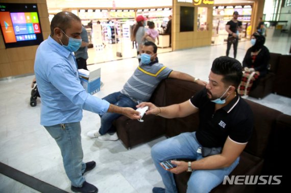 [바그다드=AP/뉴시스]지난 23일(현지시간) 이라크 바그다드 국제공항에서 신종 코로나바이러스 감염증(코로나19) 예방을 위해 사람들에게 마스크를 배포하고 있다. 2020.08.02.