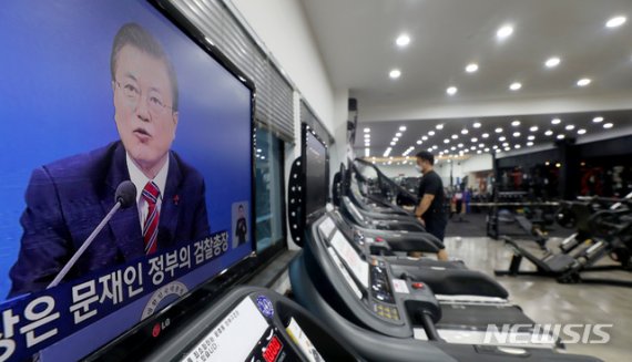 헬스장 등 실내체육시설에 대한 집합금지·운영제한이 완화된 18일 오전 서울 중구 한 헬스장에서 한 회원이 문재인 대통령의 2021 신년 기자회견을 시청하고 있다.
