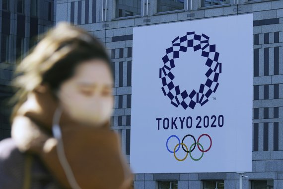 한 여성이 도쿄도청 앞에 내걸린 도쿄올림픽 대형 플래카드 앞을 지나고 있다. AP뉴시스