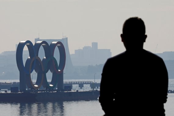 한 남성이 22일 도쿄에 설치된 올림픽 마크 조형물을 멀리서 바라보고 있다. 시야가 흐리다. 로이터 뉴스1