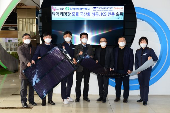 한국수력원자력과 한국에너지기술연구원 등 관계자들이 25일 국내 최초로 국산화에 성공, 한국산업규격(KS) 인증을 획득한 박막 태양광 모듈을 들고 기념촬영을 하고 있다. 한수원 제공