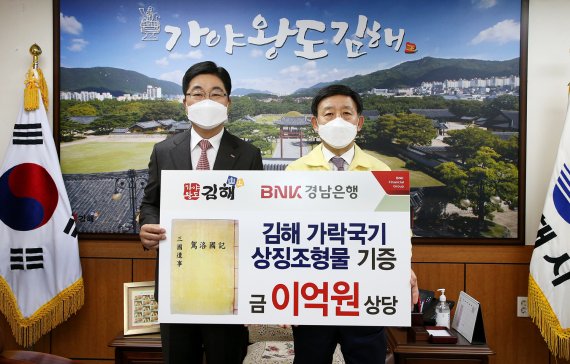 BNK경남은행 황윤철 은행장(왼쪽)이 김해시 허성곤 시장에게 가락국기 상징조형물 기증서를 전달하고 있다./제공=BNK경남은행