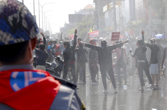 Protesters regroup after police fired warning-shots and use water cannons during a protest in Mandalay, Myanmar on Tuesday, Feb. 9, 2021. Police cracked down Tuesday on the demonstrators protesting against Myanmar’s military takeover who took to the streets in defiance of new protest bans. (AP Photo