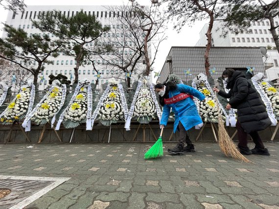 15일 오전 서울남부지법 앞을 찾은 대한아동학대방지협회 회원들이 정인이 사건 근조화환을 살피고 인근을 청소하는 모습. 대아협 제공.