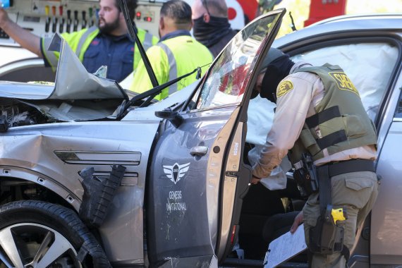 미국 로스앤젤레스(LA) 보안국 직원들이 23일(현지시간) LA 남부 랜초 팔로스 베르디스에서 발생한 전복 사고로 파손된 골프 스타 타이거 우즈가 운전하던 차량을 살펴보고 있다.AP뉴시스