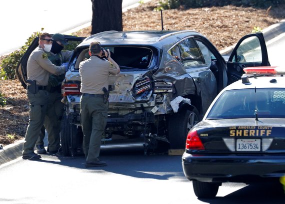 미국 로스앤젤레스 보안관들이 23일(현지시간) 전복 사고로 파손된 골프 스타 타이거 우즈의 차량을 촬영하고 있다.로이터뉴스1