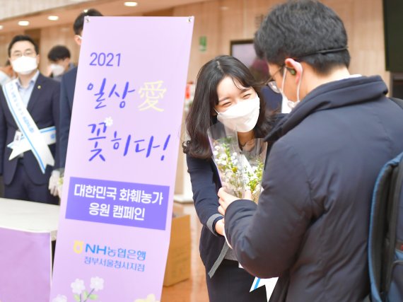 농협은행 직원이 2일 서울 세종로 정부서울청사에 출근하고 있는 공무원 고객에게 장미꽃을 전달하고 있다.