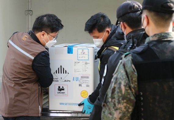 [천안=뉴시스]강종민 기자 = 26일 오후 충남 천안실내배드민턴장에 마련된 신종 코로나바이러스감염증(코로나19) 중부권역 예방접종센터에 화이자사가 제조한 백신이 도착, 방역당국 관계자들이 차량에서 내리고 있다. (공동취재사진). photo@newsis.com