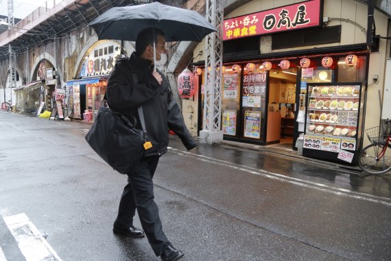 지난 8일 일본 도쿄에서 코로나19 확산 방지를 위해 마스크를 쓴 한 시민이 술집과 식당이 즐비한, 거의 텅 빈 거리를 걷고 있다. 뉴시스
