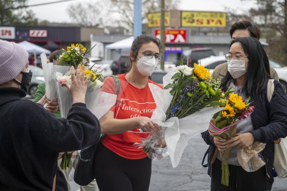 시민 두명이 17일(현지시간) 미국 애틀랜타의 골드 스파 밖에 마련된 임시 추모장으로 꽃을 들고 걸어가고 있다. 지난 16일 이곳을 포함해 애틀랜타 지역 스파 3곳에서 총격 사건으로 8명이 사망했다. 애틀랜타 근교 그위넷 카운티 경찰은 아시아계 업소에 대한 순찰을 늘리기 시작했다.AP뉴시스