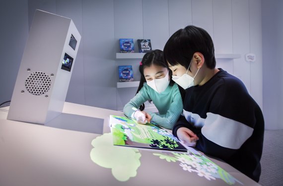 [서울=뉴시스]아이들이 리얼리티 북스에서 AR로 실감나는 콘텐츠를 감상하고 있는 모습 (사진=SK텔레콤 제공) 2021.03.23