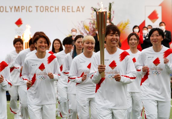 일본 여자 축구대표팀 선수들이 25일 후쿠시마현 축구시설인 J빌리지에서 열린 도쿄올림픽 성화 봉송행사에서 첫 주자로 성화를 들고 뛰고 있다. 로이터 뉴스1